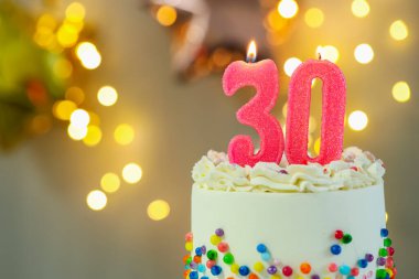 30. yaş günü. Kek üzerindeki mumların yanma sayısı bulanık arka planda ışıklar, yakın plan ve metin için boşluk. Bokeh etkisi