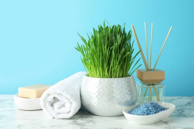 Açık mavi arkaplan üzerine beyaz mermer masa üzerinde buğday çimi ile spa bileşimi