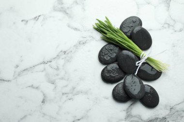 Spa stones and wheatgrass on white marble background, flat lay. Space for text