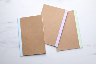 Different copybooks on white marble table, flat lay