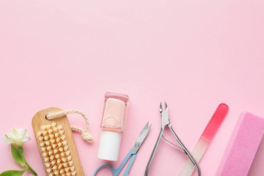 Farklı manikür aletleri ve pembe arka planda çiçek seti. Metin için boşluk