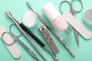 Turkuaz zemin üzerinde farklı manikür araçları kümesi, düz yatar