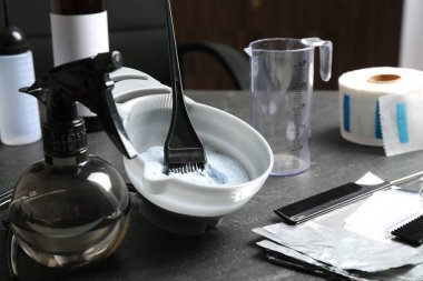 Kuaför salonundaki gri masada çamaşır suyu ve kuaför aletleri.