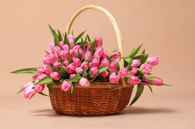 Hasır sepette bej arka planda güzel laleler.