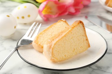 Lezzetli kek parçaları, Paskalya yumurtaları ve laleler açık mermer masada, yakın plan.