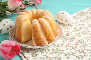 Lezzetli kek, Paskalya yumurtaları, söğüt dalları ve açık mavi masadaki laleler, yakın plan.