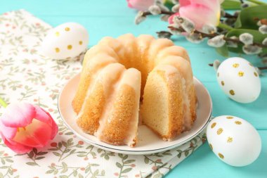 Lezzetli kek, Paskalya yumurtası, söğüt dalları ve açık mavi ahşap masada laleler, yakın plan.