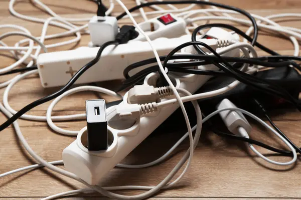 Uzatma güç panoları ahşap zemindeki tıkaçlarla aşırı yüklenmiş, yakın plan.