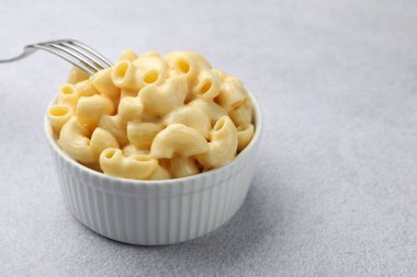 Peynir soslu lezzetli makarna ve gri masada çatal, yakın plan. Metin için boşluk