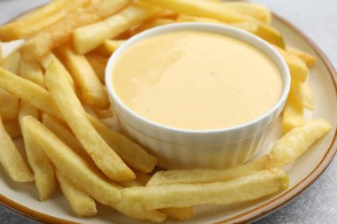 Tabakta lezzetli peynir sosu ve masada patates kızartması, yakın plan.