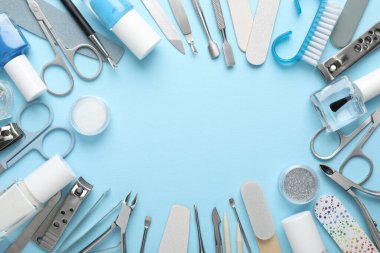 Açık mavi arkaplandaki farklı manikür aletlerinin çerçevesi düz. Metin için boşluk