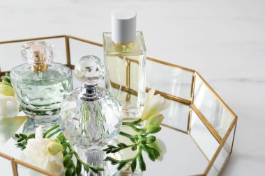 Parfümlü tepsi ve güzel çiçekler beyaz masada, yakın plan.