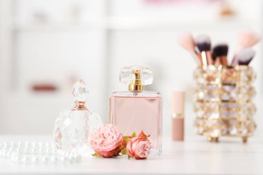 Parfüm şişeleri ve beyaz masada güzel çiçekler.