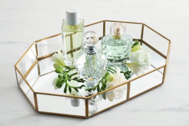 Parfümlü tepsi ve beyaz masada güzel çiçekler.