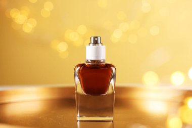 Bir şişe aromatik parfüm metal tepside bej arka planda bulanık ışıklarla, yakın plan. Bokeh etkisi