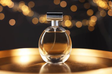 Bir şişe aromatik parfüm metal tepside siyah arka planda bulanık ışıklarla, yakın plan. Bokeh etkisi