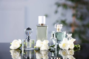 Ayna yüzeyinde bulanık arka planda aromatik parfüm şişeleri ve çiçekler