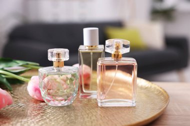 Aromatik parfüm şişeleri ve çiçekler ahşap masada bulanık arka planda, yakın plan