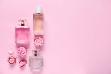 Parfüm şişeleri ve pembe arka planda güzel çiçekler. Metin için boşluk