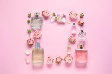 Parfümlü şişeler ve pembe arka planda güzel çiçekler. Metin için boşluk