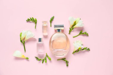 Parfüm şişeleri ve pembe arka planda güzel çiçekler.