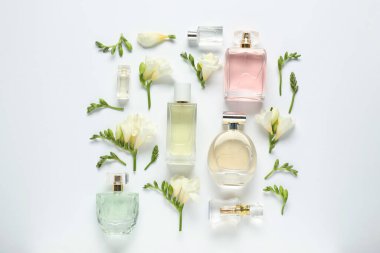 Parfüm şişeleri ve beyaz arka planda güzel çiçekler.