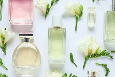 Parfüm şişeleri ve beyaz arka planda güzel çiçekler.