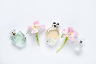 Parfüm şişeleri ve beyaz arka planda güzel çiçekler.