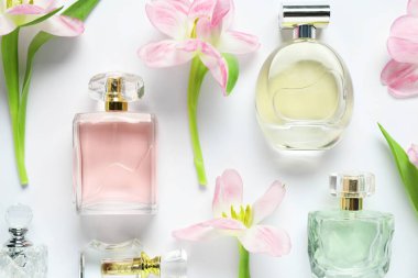 Parfüm şişeleri ve beyaz arka planda güzel çiçekler.