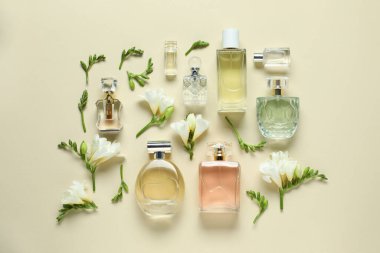 Parfüm şişeleri ve bej arka planda güzel çiçekler.