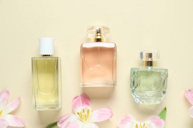 Parfüm şişeleri ve bej arka planda güzel çiçekler.