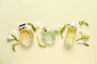 Parfüm şişeleri ve bej arka planda güzel çiçekler.