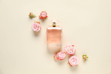 Bir şişe parfüm ve bej arka planda güzel çiçekler.