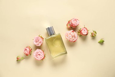 Bir şişe parfüm ve bej arka planda güzel çiçekler.
