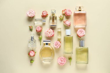 Parfüm şişeleri ve bej arka planda güzel çiçekler.