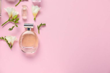 Parfüm şişeleri ve pembe arka planda güzel çiçekler. Metin için boşluk