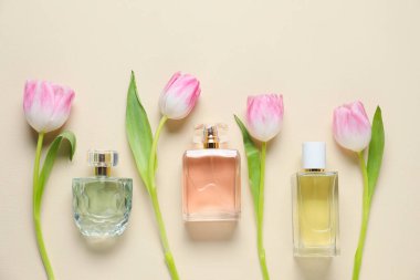 Parfüm şişeleri ve bej arka planda güzel çiçekler.