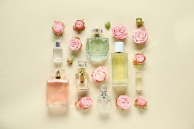 Parfüm şişeleri ve bej arka planda güzel çiçekler.