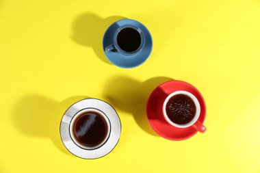 Sarı arka planda aromatik kahve içilen farklı bardaklar.