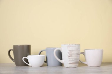 Açık ahşap masada bej arka planda bir sürü renkli fincan var. Metin için boşluk