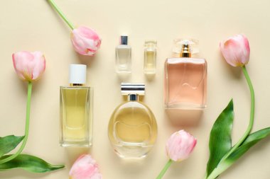Parfüm şişeleri ve bej arka planda güzel çiçekler.