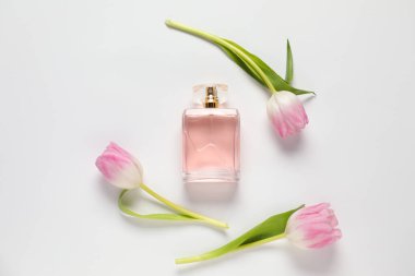 Bir şişe aromalı parfüm ve beyaz arka planda güzel laleler.