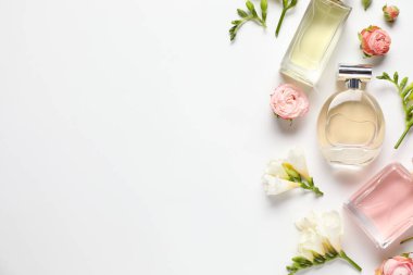 Düz kompozisyonda aromatik parfüm şişeleri ve beyaz arka planda güzel çiçekler vardı. Metin için boşluk