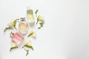 Düz kompozisyonda aromatik parfüm şişeleri ve beyaz arka planda güzel çiçekler vardı. Metin için boşluk