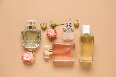 Düz kompozisyonda aromatik parfüm şişeleri ve bej arka planda güzel çiçekler vardı.