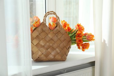 Pencere pervazında hasır çantanın içinde güzel laleler