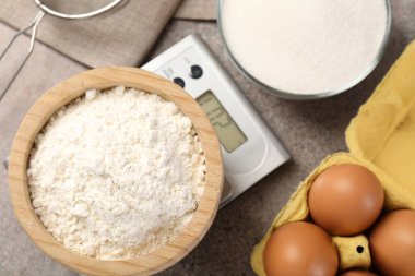 Mutfak terazisi, bir kase un ve gri desenli masa üzerindeki diğer ürünler.