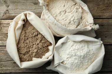 Tahta masada, düz bir zeminde, çuvalda farklı türde un bulunur.