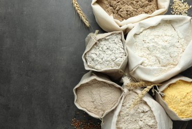 Gri masadaki poşetlerdeki farklı tipte un, düz. Metin için boşluk