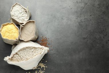 Gri masadaki poşetlerdeki farklı tipte un, düz. Metin için boşluk